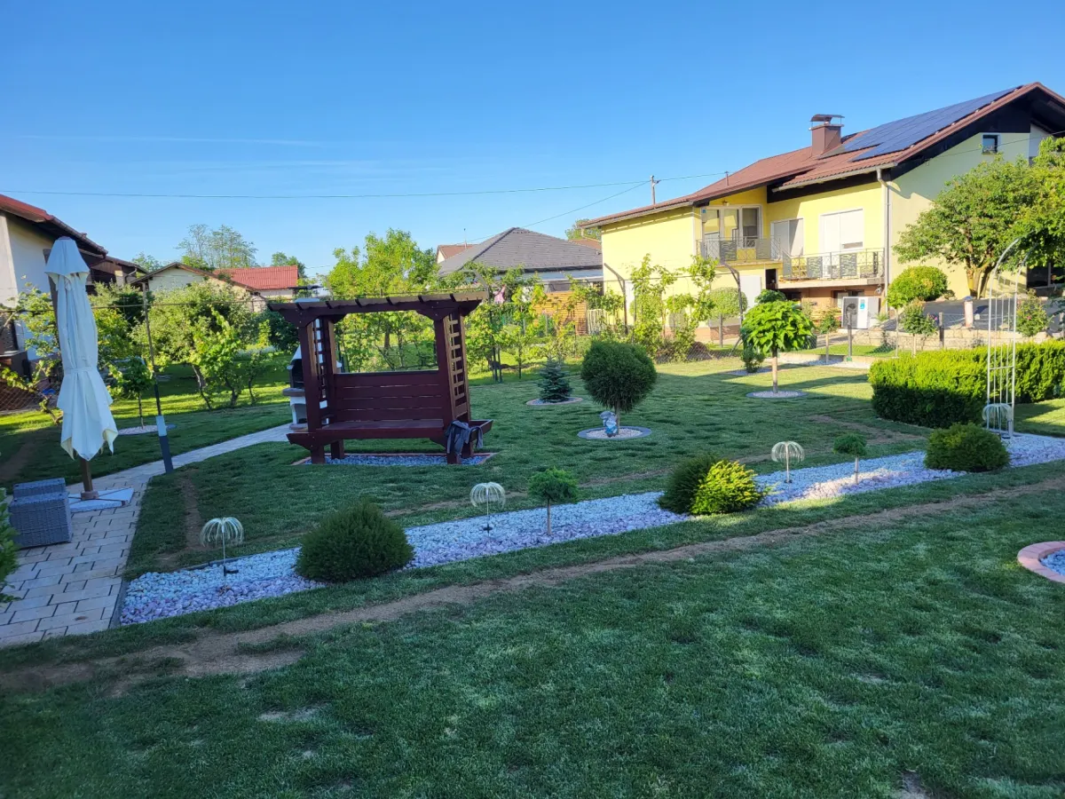 Urejen vrt s travo, okrasnimi grmi in pergolo